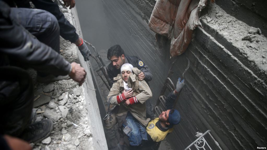 Syria Civil Defense members help an unconscious woman from a shelter in the besieged town of Douma, Eastern Ghouta, Damascus, Syria, Feb. 22, 2018.   Syrians in Ghouta Tweet for Their Lives as Bombs Rain Down  “For God’s sake help us!” reads a message on Twitter attached to a video showing two small girls, bleeding and crying in a smoky, chaotic house. It is part of a social media campaign surrounding the crisis in Ghouta, Syria, where more than 400 civilians have been killed in the past six days, according