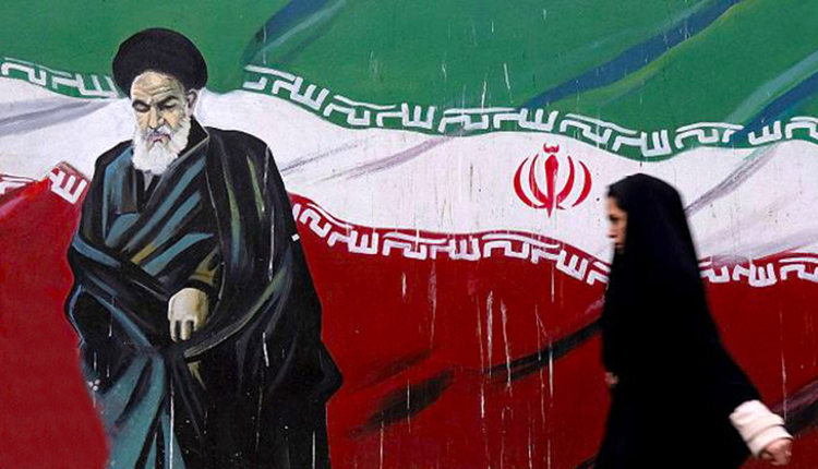 أمرأة إيرانية تمشي أمام صورة مؤسس الجمهورية الإسلامية الإيرانية