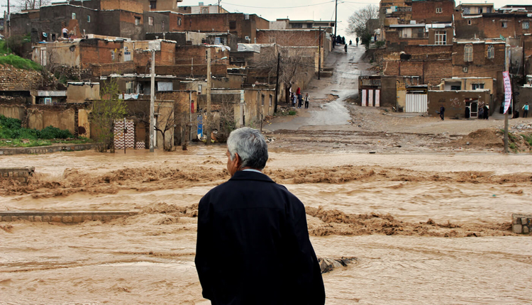 مواطن إيراني واقف أمام السيول 