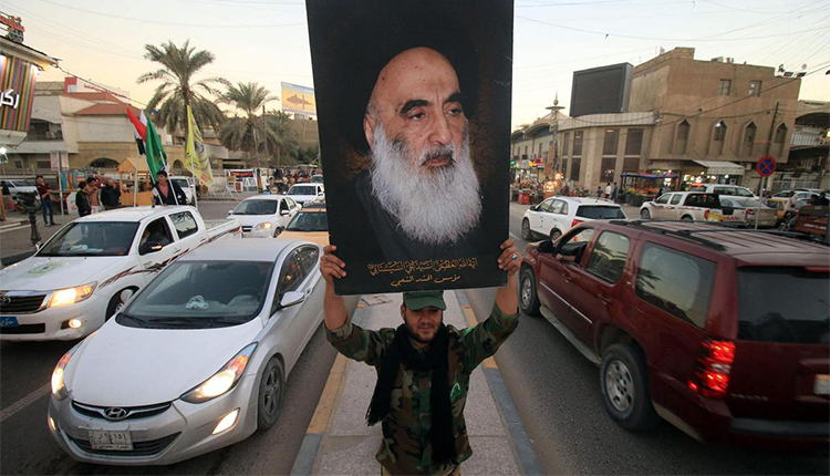 عراقي يرفع صورة السيستاني، المرجع العليا للشيعة