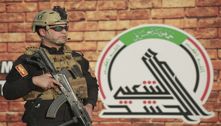 جندي أمام شعار الحشد الشعبي