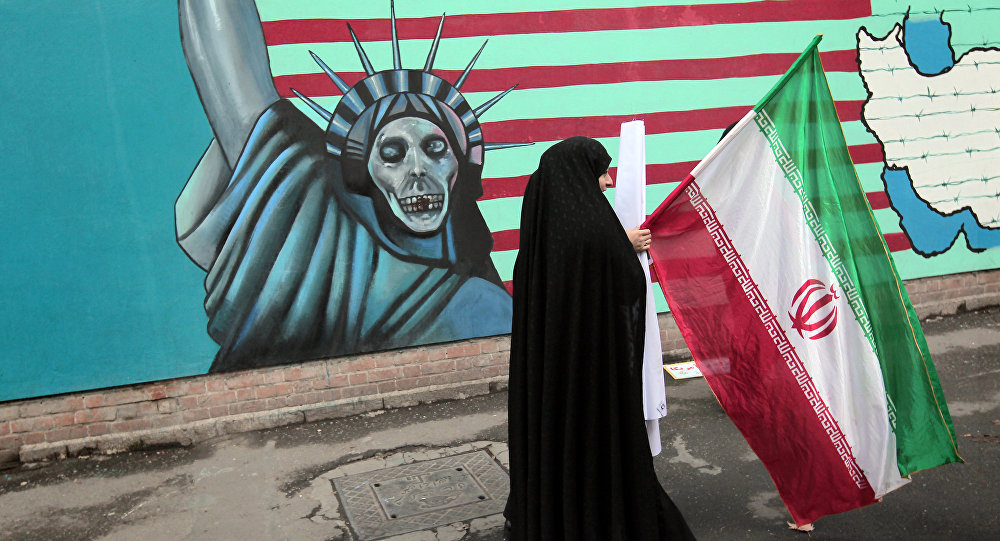 إيرانية تحمل علم بلاده أمام جدارية 