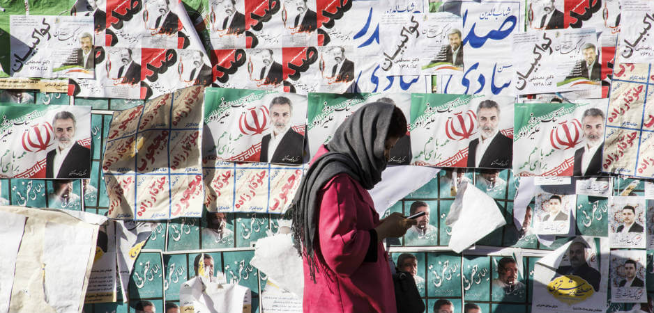إيرانية تمشي أمام بوسترات أنتخابية