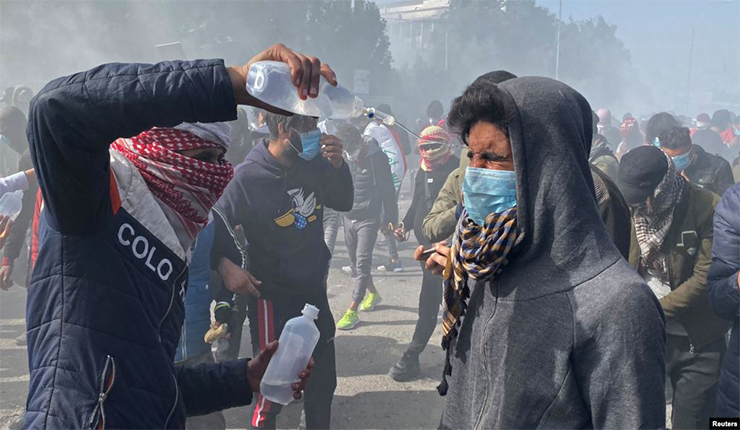 متظاهرون يحمون أنفسهم من غاز مسيل للدموع