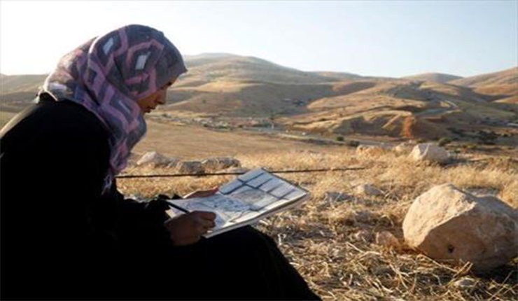الرسامة الفلسطينية خديجة بشارات ترسم في غور الأردن بالضفة الغربية  (رويترز)