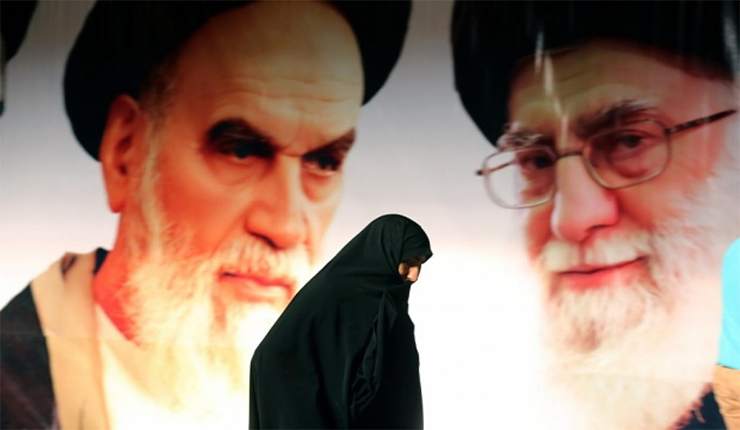 إيرانية تمشي أمام صورتي المرشدين السابق والحالي لإيران