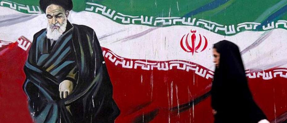 أمرأة إيرانية تمشي أمام صورة مؤسس الجمهورية الإسلامية الإيرانية