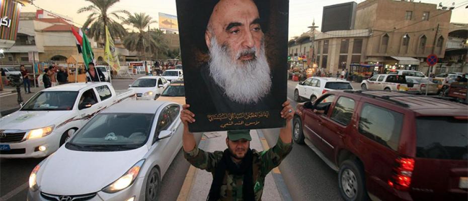 عراقي يرفع صورة السيستاني، المرجع العليا للشيعة