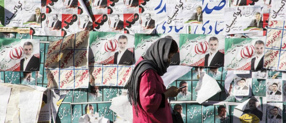 إيرانية تمشي أمام بوسترات أنتخابية
